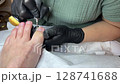 Professional pedicure session. Toenail care treatment. Woman foot cleaning. Nail technician working. Beauty salon procedure. Foot hygiene service. Spa therapy moment. Black gloves and machine. 128741688