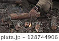 Man building campfire with mossy logs in forest setting 128744906
