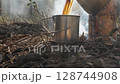 Pouring hot drink into metal mug at forest campsite 128744908