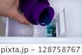 Woman pours liquid laundry detergent into compartment of washing machine, close-up. domestic washing machine 128758767