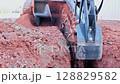 Heavy trenching machinery digs into dry ground, creating trench in construction area 128829582