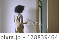 A young woman is decorating the walls during the renovation of her apartment. 128839464