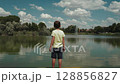 Young Boy Watching Lake Fountain on Sunny Dock 128856827