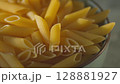 Uncooked Penne Pasta in Bowl Close-Up Panning Camera Shot 128881927