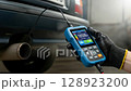 Hand holding diagnostic tool and checking vehicle pollution smoke. Car exhaust emissions test. 128923200