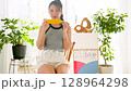 Smiling young woman holding corn in her hand in her room 128964298