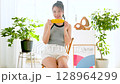 Smiling young woman holding corn in her hand in her room 128964299