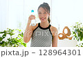 Smiling young woman enjoying summer refreshing drink in room 128964301