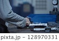 Close-up of an engineer performing manual inspection and measuring of machined metal components in an industrial setting. Concept of quality control in precision manufacturing 128970331