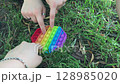 Group of people are playing with a colorful toy that has a rainbow design 128985020