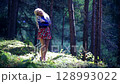 Blonde woman in short skirt sings in sunny forest on a warm summer day 128993022