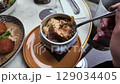 A person prepares and enjoys a warm bowl of soup, savoring it 129034405
