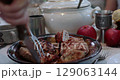 POV hands serve and cut stuffed turkey roll using knife and two prong fork on Thanksgiving dinner table with vintage crockery. Traditional Thanksgiving turkey roulade roasted on grill. Serving dinner 129063144