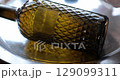 Clean and degrease surface of patterned glass wine bottle closeup. Use rag with cleaning agent, wash with protective gloves, scrub with hands. Removing stains and dirt, prepare bottle for new applying 129099311