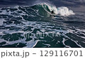 Dynamic surfer glides inside massive ocean wave with storm clouds above symbolizing strength adventure freedom challenge adrenaline exhilaration perseverance 129116701