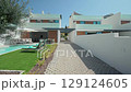 White modern villas with private swimming pool, artificial grass, olive tree, sunbeds and outdoor furniture, are displaying a luxurious and relaxing atmosphere 129124605