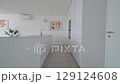 Minimalist white kitchen showcases modern design, featuring an island, integrated appliances, and artistic details, creating a clean and stylish culinary space 129124608
