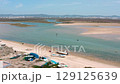 Natural park landscape in algarve region featuring shallow, calm waters with tourists paddle boarding, enjoying sunny weather and recreational water activities near ria formosa coastal environment 129125639