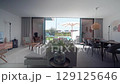 Sunlight illuminates a contemporary living room, showcasing a seamless transition to an outdoor oasis with a sparkling pool and patio area, complete with modern furniture and lush greenery 129125646