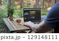 Video editing on laptop outdoors with tea and natural surroundings 129148111