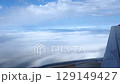 View of airplane wing above clouds during a sunny flight 129149427