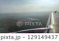 Wing view of plane landing in sunset over rural landscape 129149437