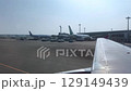 Sunny Day Airport View with Airplanes Parked Seen from a Plane Window 129149439