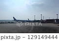 Airplanes Await Takeoff at Busy Airport under Clear Sky 129149444