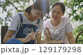 Slow motion Asian mother and daughter drawing a picture with paint and brush together in park backdrop. 129179298