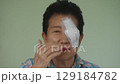 elder woman covering protection on left eye smiling after cataract surgery in cream background 129184782