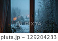 Cozy indoor view of a snow-covered garden and bare trees on a winter day. 129204233