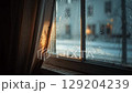 Rain-streaked window view, warm sunlight filters through a curtain. 129204239