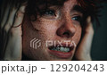 Close-up portrait of a young woman screaming in pain or stress, showing strong emotion. 129204243