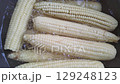 Boiling corn cobs. Close up of white fresh corn cobs in boiling water 129248123