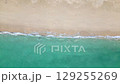 Aerial drone view (top down) to sea waves and white sand. Turquoise blue water, tropical theme. Concept of relaxation in pure nature. 129255269