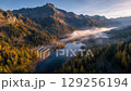 沐浴在秋色中的高山湖泊和山谷中升起的晨霧的全景 129256194