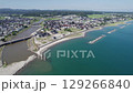 Aerial drone view of a coastal town in Noto Peninsula Suzu, Japan. Blue sea, breakwaters, rivers, and a mix of traditional and modern homes highlight this peaceful regional landscape on a sunny day. 129266840
