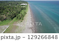 Drone footage of Hachigasaki Beach in Noto, Japan. The coastline features lush pine forest meeting a tranquil shoreline and shallow turquoise sea. An ideal scenic blend of land and water in summer. 129266848
