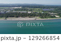 Drone footage of Hachigasaki Beach in Noto, Japan. The shot captures turquoise waters, a sandy shoreline, pine forests, and inland farmland, showing a perfect blend of nature and quiet development. 129266854