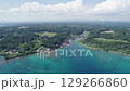 Drone footage of Anamizu, Sora area in Noto, Japan. The image captures a quiet coastal village, lush green forest, and turquoise sea blending into scenic inland farmland. Peaceful summer atmosphere. 129266860