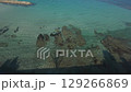 FPV drone flies low over the crystal-clear waters of Goshikigahama Beach in Noto, Japan. The shoreline, rock reef, and vibrant blue sea create a stunning and immersive coastal flight experience. 129266869