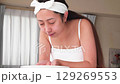 一位年輕的亞洲女子正在洗臉。 129269553