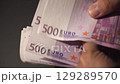 A hand counts 500 euro banknotes in preparation for a financial transaction 129289570