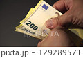A hand counts 200 euro banknotes in preparation for a financial transaction 129289571