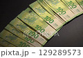 hand placing and neatly arranging stacks of 100 Euro banknotes on a table 129289573