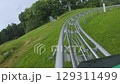 Exciting ride on a mountain coaster winding through lush green hills 129311499
