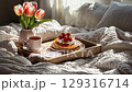 Cozy breakfast in bed with pancakes, strawberries, coffee, and tulips on a soft blanket 129316714