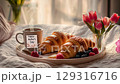 Morning coffee and croissants paired with fresh berries and tulips in a cozy setting 129316716