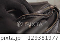 Hands of a thief wearing black gloves stealing wallet from black leather bag 129381977