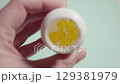 Close up of a hand presenting a white plastic bottle filled with yellow softgels 129381979